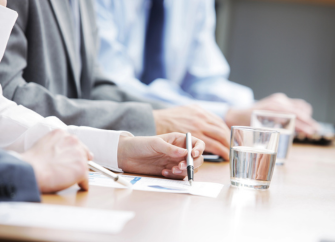 Hände und Arme von Geschäftsleuten, die bei einem Meeting mitschreiben