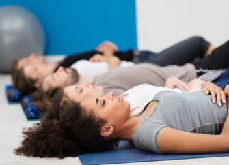 Menschen liegen auf einer Gymnastikmatte und entspannen sich